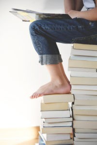 Person Sitting on Stacks of Books