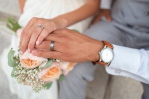 Two hands with wedding rings over a bouquet