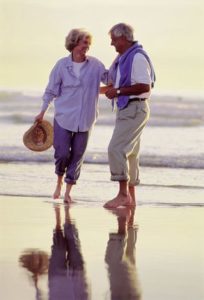 Two elderly people walking on the beach