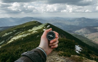 Person looking at compass in front of mountain