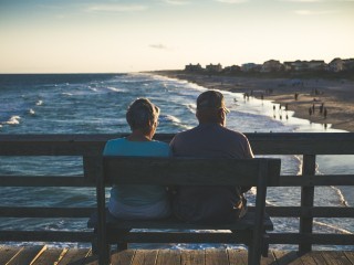 Two people sitting on a dock on the ocean