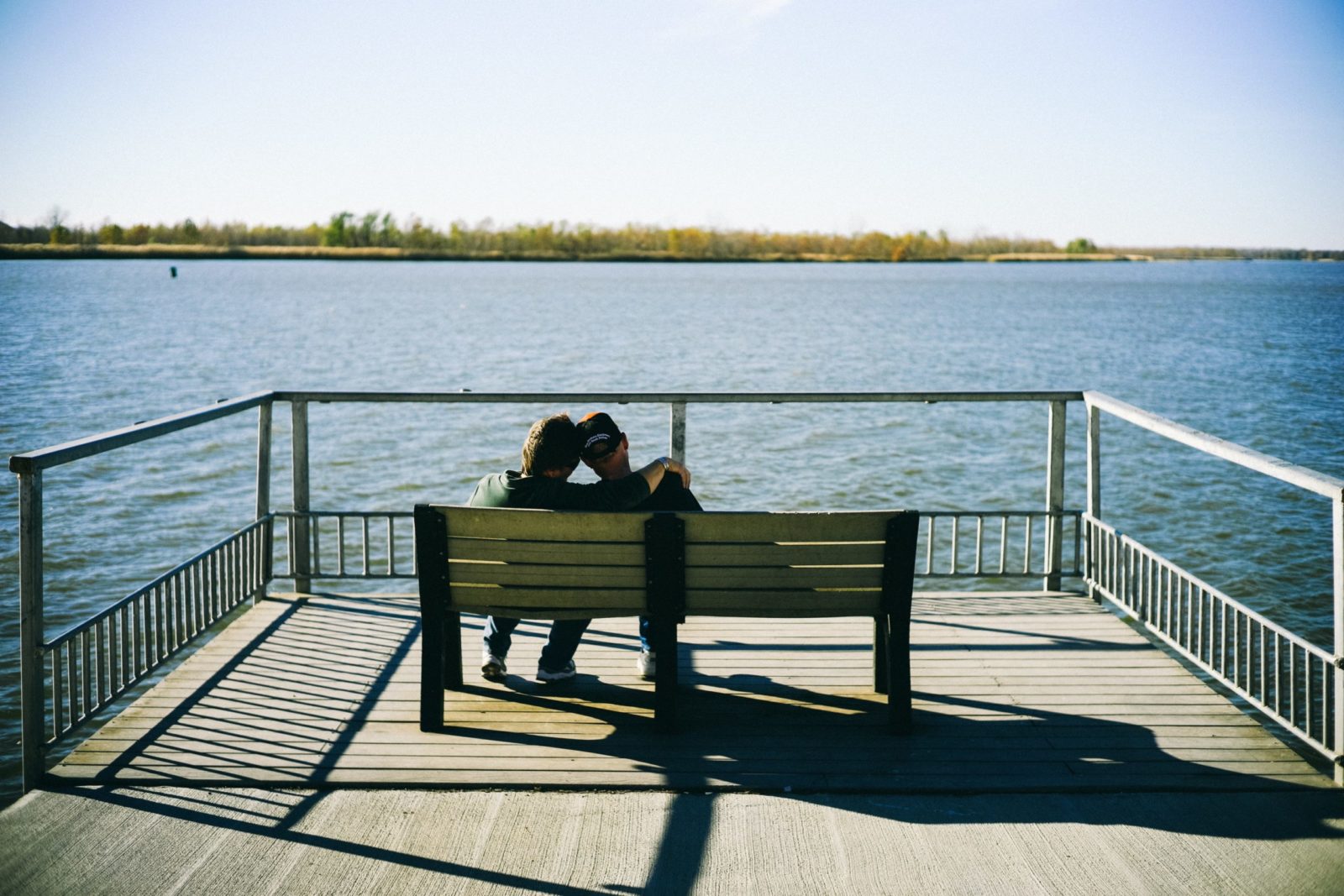 a couple sitting on a bench on a doc
