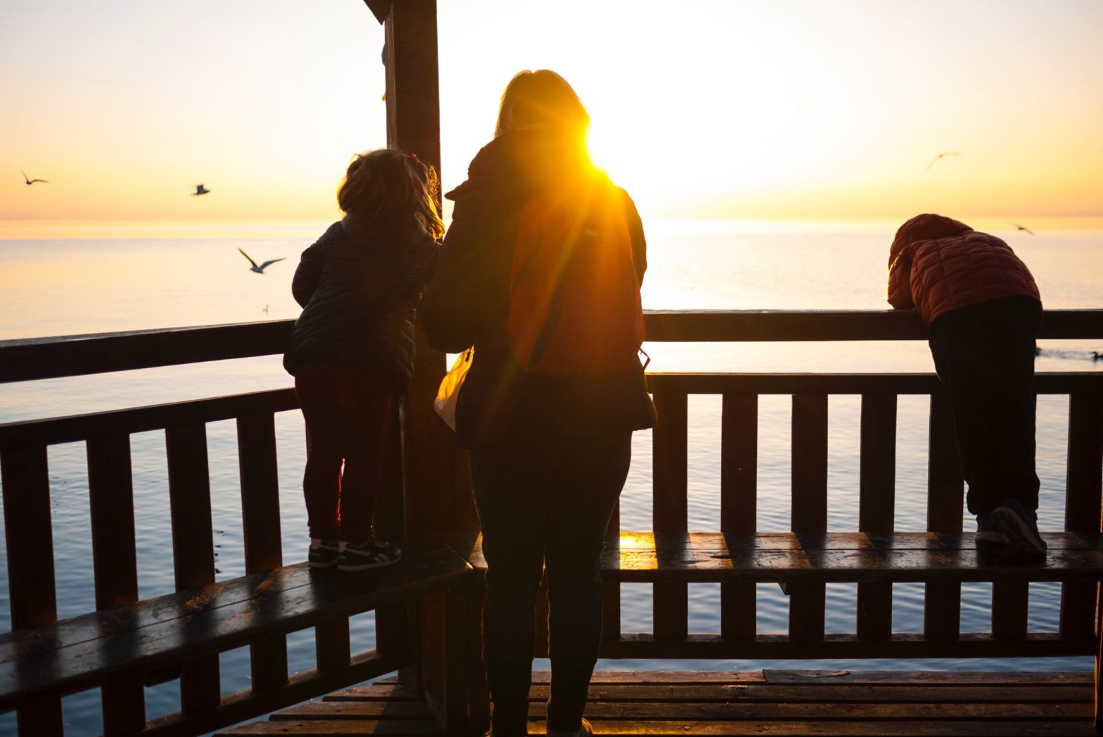 A mom and two children on a deck on the water