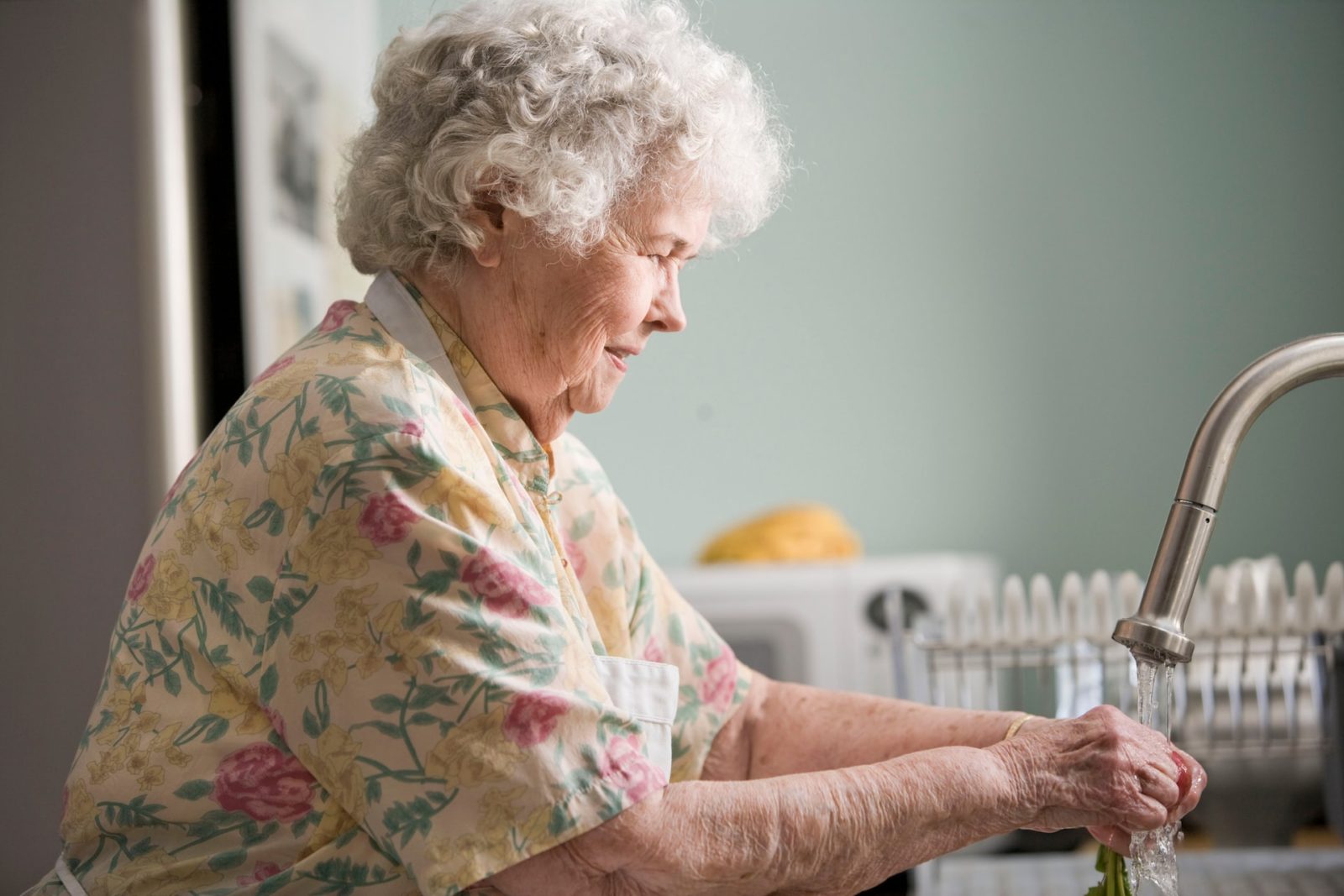 woman washing her hands at kitchen sink