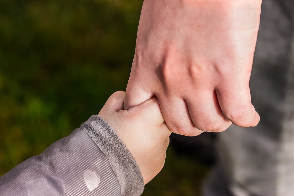 adult holding a toddler's hand